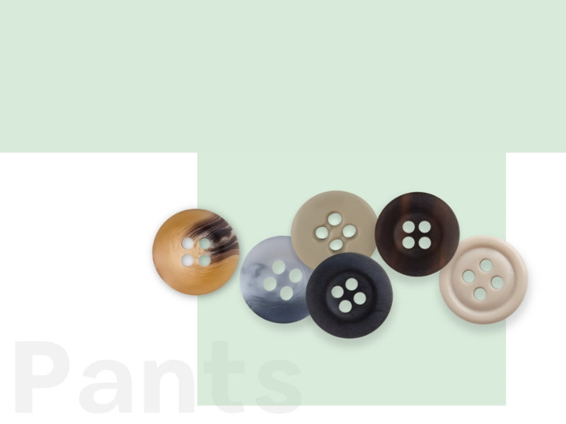 Six assorted four-hole buttons in brown, gray, and neutral tones are arranged in a cluster on a light green and white background. The word Pants is faintly visible in the lower left corner.