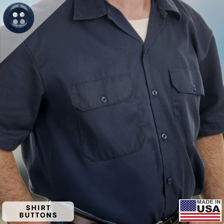 A man wearing a dark blue short-sleeve button-up shirt with two chest pockets displays a visible “Made in USA” label and features Work Shirt Buttons manufactured to military specifications for enhanced durability and long-lasting wear.