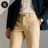 Wearing a navy blazer accented with Khakis, Chinos and Casual Cotton Pant Buttons, paired with a white shirt and tan casual pants, this individual stands with one hand in their pocket, accessorized by a watch.