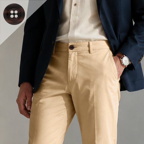 Wearing a navy blazer accented with Khakis, Chinos and Casual Cotton Pant Buttons, paired with a white shirt and tan casual pants, this individual stands with one hand in their pocket, accessorized by a watch.