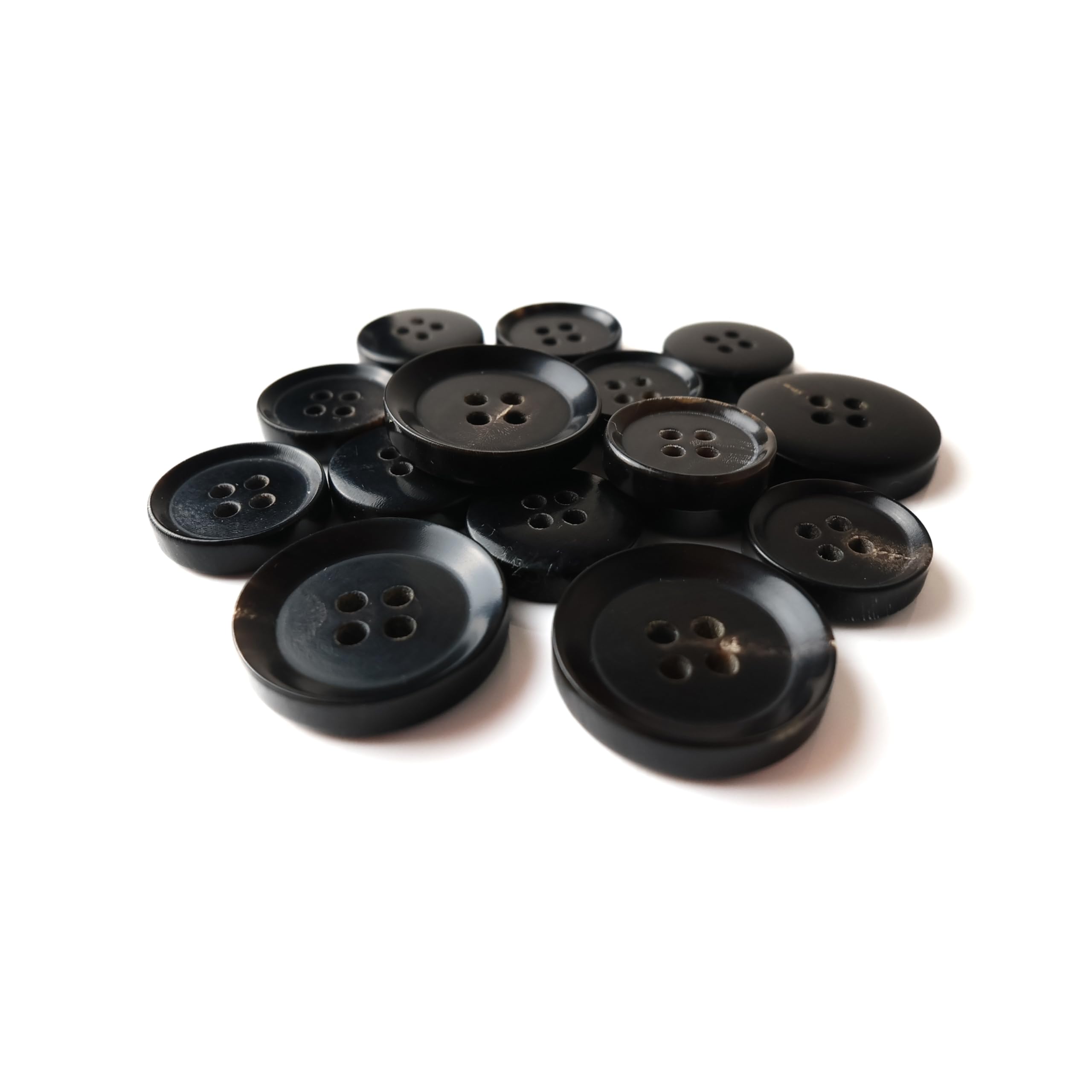 A pile of Buffalo Horn Suit Buttons, all black with four holes, arranged on a white background.