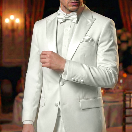 A man in an elegant white tuxedo featuring black satin Tuxedo Suit Buttons and a bow tie stands indoors against a blurred formal background.