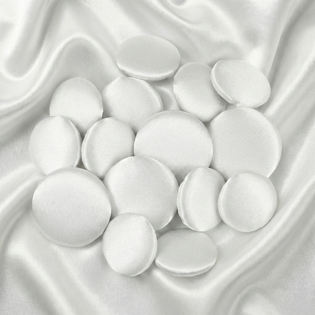Tuxedo Suit Buttons: Round white satin buttons displayed on smooth, shiny white satin fabric—ideal for accenting formalwear or complementing elegant tuxedo attire.