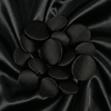 Tuxedo Suit Buttons in shiny black satin, artfully arranged on smooth black satin fabric with gentle, wavy folds.