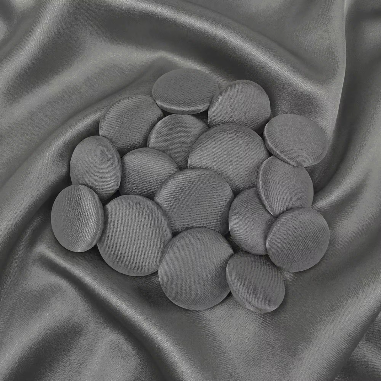 Tuxedo Suit Buttons in round gray velvet are displayed on matching satin fabric, reflecting the refined elegance and classic style of traditional formalwear.