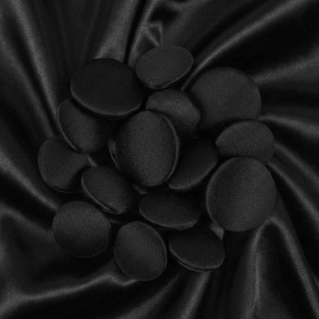 A cluster of Tuxedo Suit Buttons rests on smooth, shiny black satin fabric.
