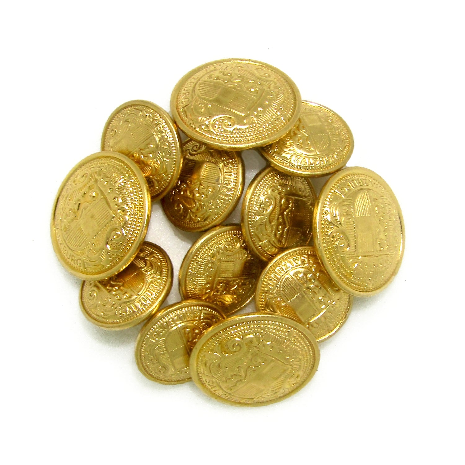 A pile of shiny Salzburg Crest Design Metal Blazer Buttons featuring intricate coat of arms details—ideal for replacing blazer buttons.