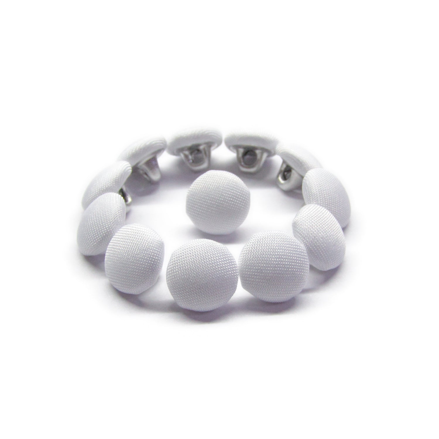 The Taffeta Bridal Buttons bracelet features white silk fabric buttons, inspired by elegant wedding dress details, displayed in a circular shape on a white background.