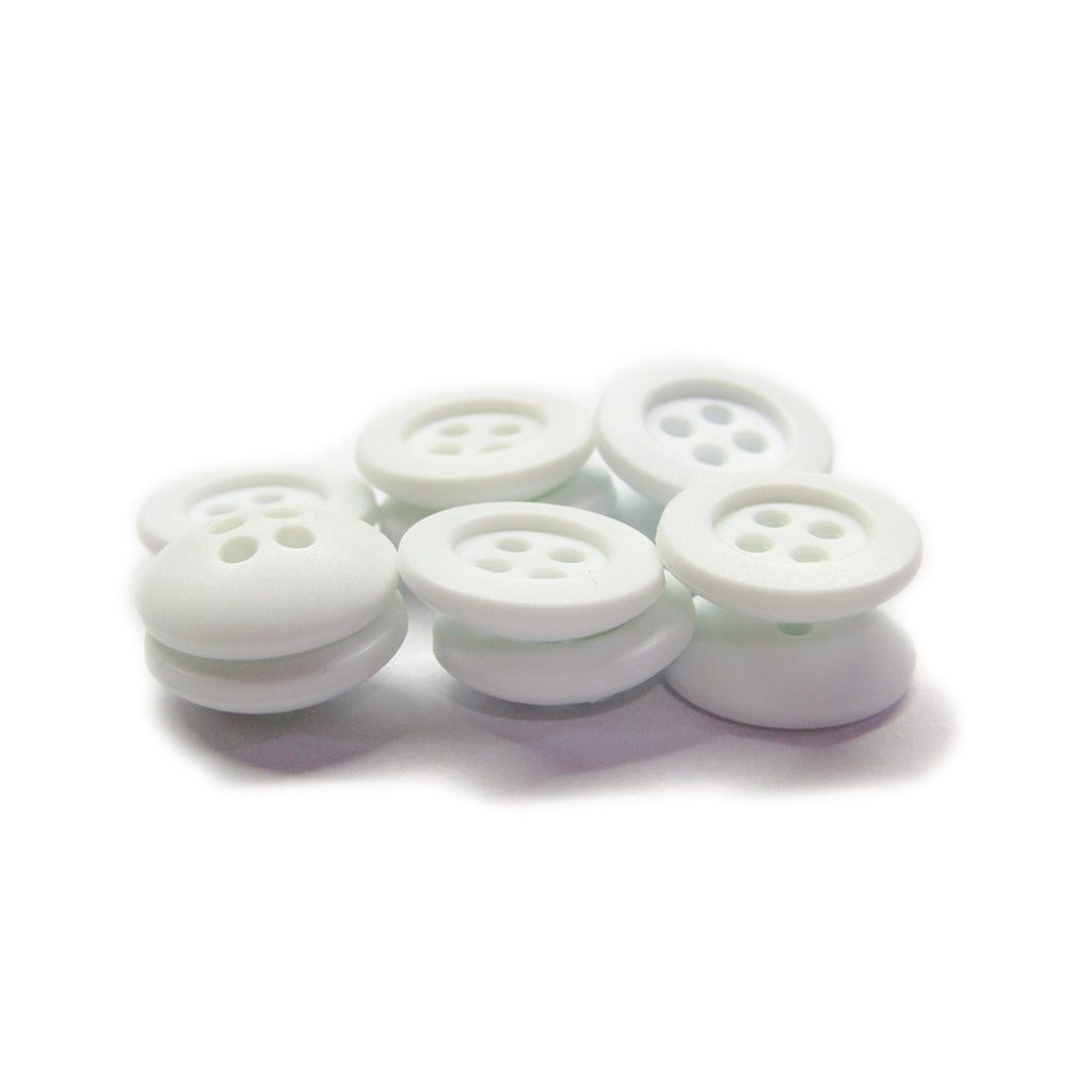 A pile of small white Rubber Shirt Buttons with four holes, scratchproof, scattered on a white surface—ideal for children's clothing.