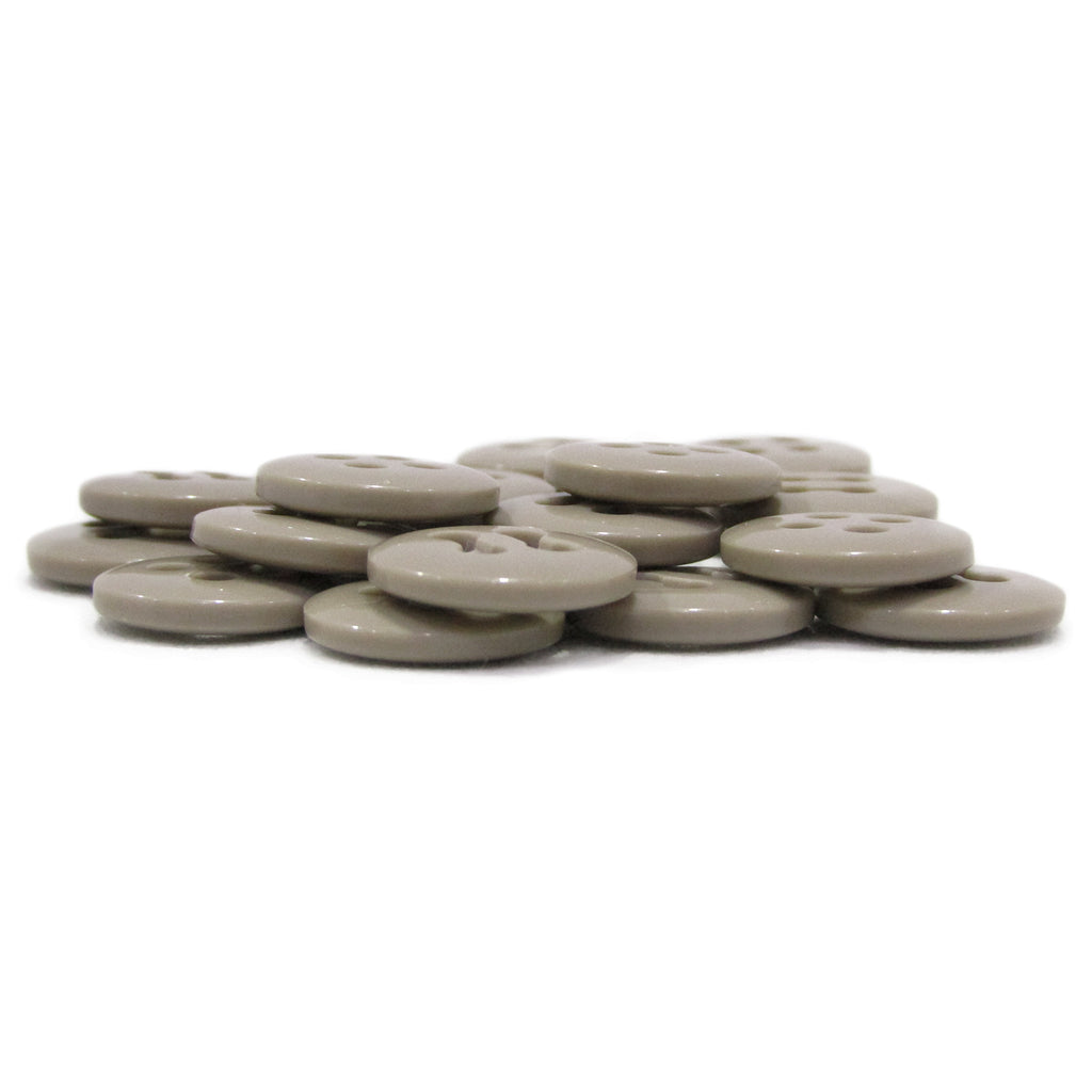 A stack of flat, round, light brown Trouser Fly Pant Buttons arranged on a white surface.