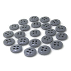 A collection of scattered gray Trouser Fly Pant Buttons, featuring two- and four-hole designs, displayed on a white background.