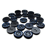 A collection of dark blue and black round Commercial Food Service Buttons with two holes, scattered on a white surface.