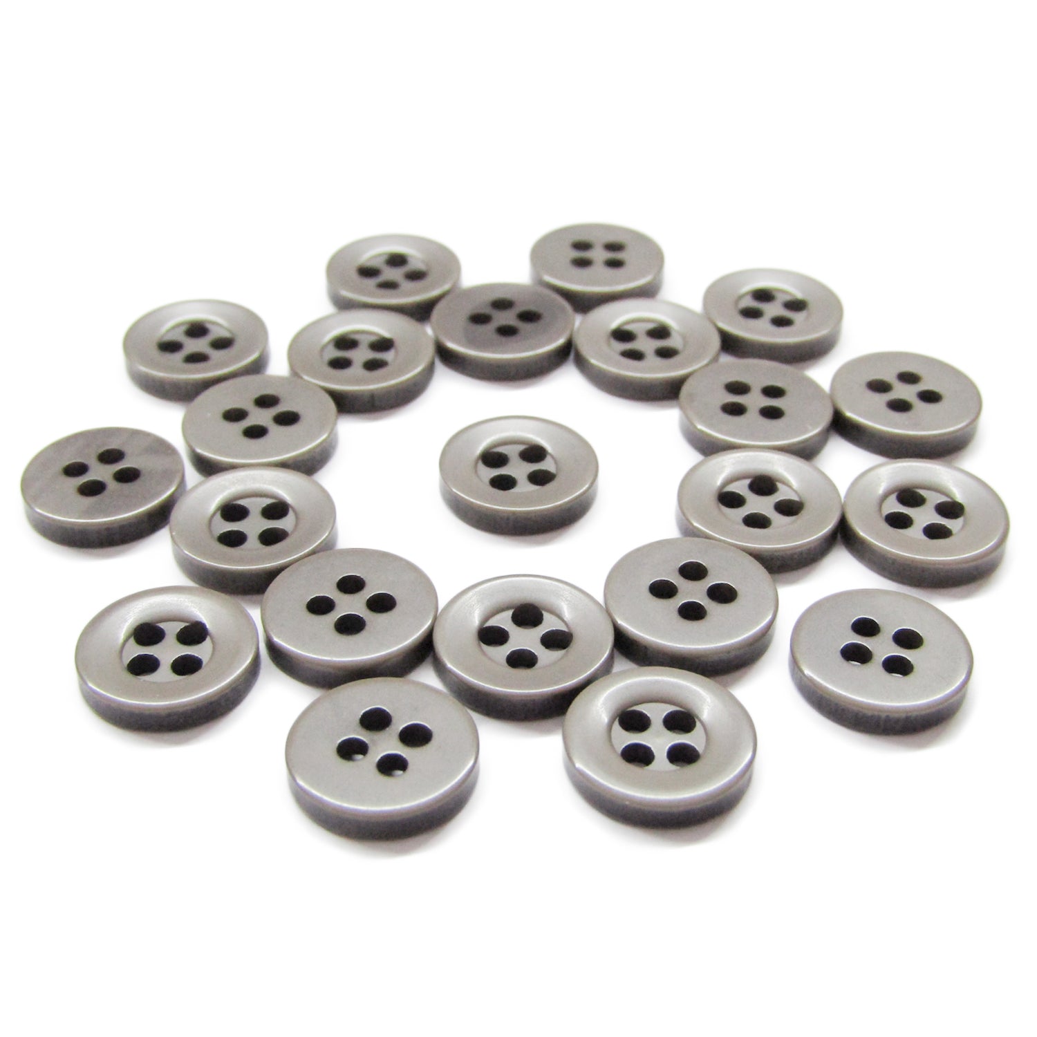 Several Workshop Uniform Shirt Buttons, small, round, gray, and made of durable nylon with four holes, are scattered on a white surface.