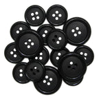 A pile of black round Luxury Suit Buttons with four holes each, including vegan options.