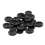 A pile of Replacement Shirt Buttons scattered on a white surface, featuring classic black, four-hole poly-nylon buttons ideal for any tailor’s kit.