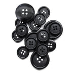 A pile of Vegan Faux Horn Suit Buttons, black with four holes and in various sizes, displayed on a white background.
