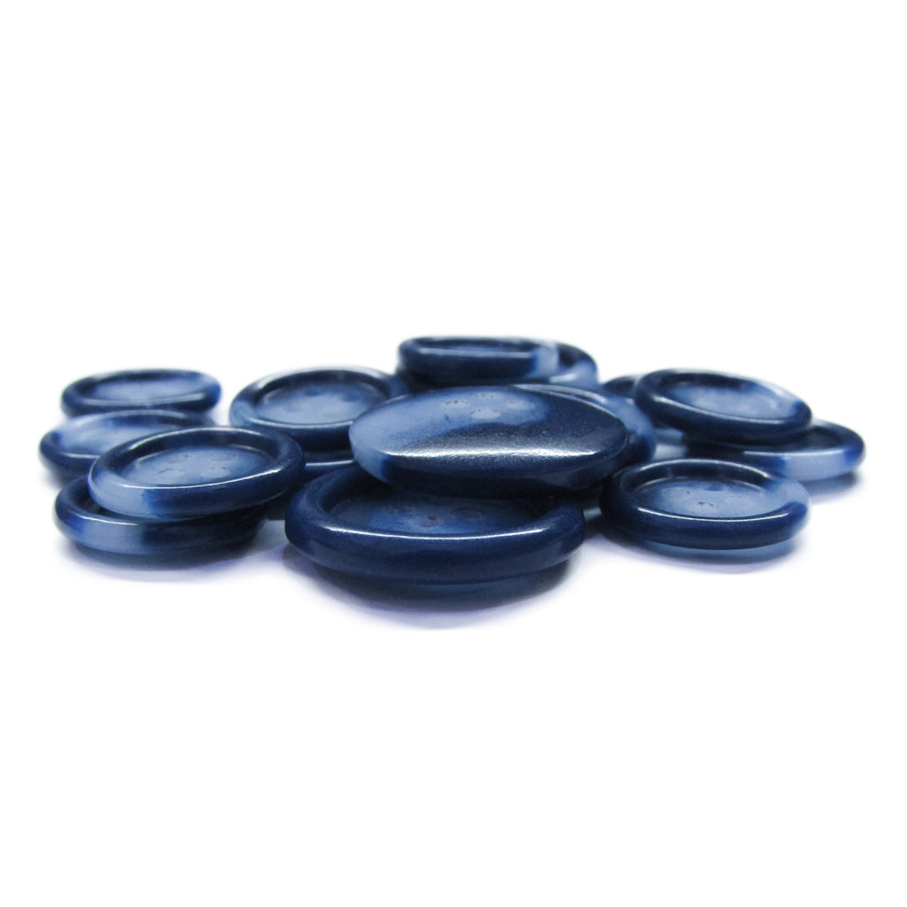 A pile of smooth, flat, translucent blue Luxury Suit Buttons on a white background, evoking the look of elegant accents for upscale ensembles.
