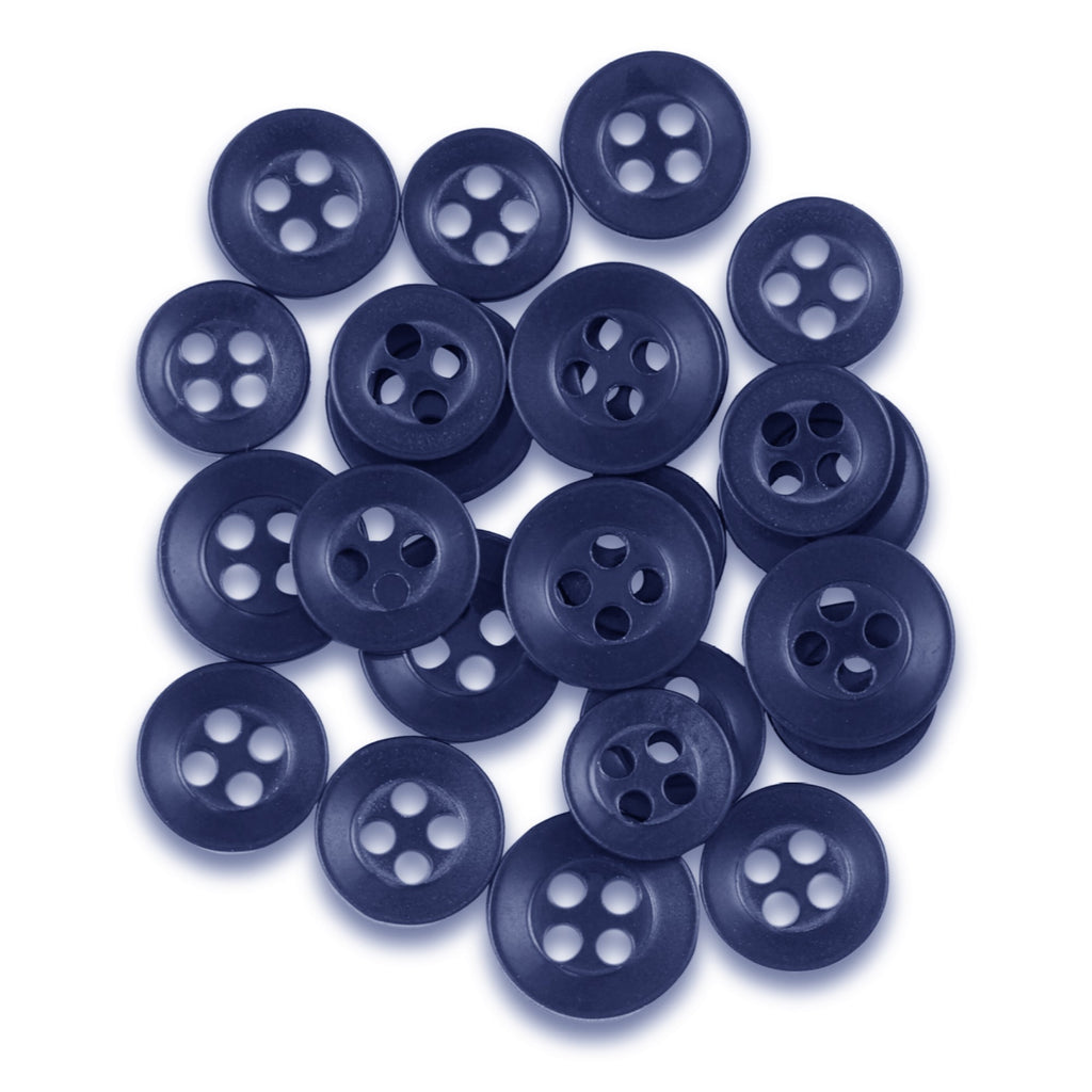 A pile of dark blue, matte finish Replacement Shirt Buttons with four holes is scattered on a white background—ideal for any tailor's kit.
