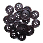 A pile of Luxury Suit Buttons, dark and round with four holes, arranged on a white background.