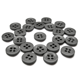 A set of Workshop Uniform Shirt Buttons, black with four holes, displayed in a loose, scattered arrangement on a white background.