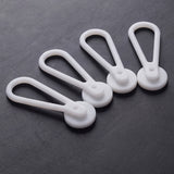 Four teardrop-shaped, white plastic Collar Extenders—perfect for expanding your collar size—are arranged on a dark textured surface.