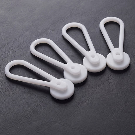 Four teardrop-shaped, white plastic Collar Extenders—perfect for expanding your collar size—are arranged on a dark textured surface.