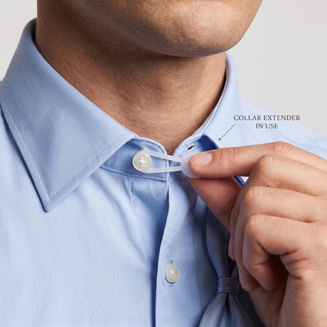 A person uses collar extenders on a light blue dress shirt to add more room at the collar.