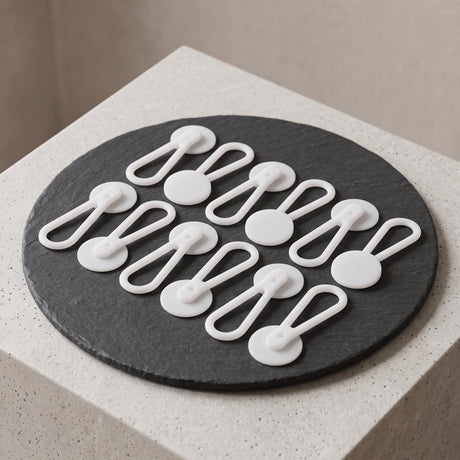 Twelve Collar Extenders are arranged neatly on a round black slate atop a light stone surface.
