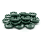 A stack of green Work Shirt Buttons 22 Pack, each with four holes, arranged on a white surface.