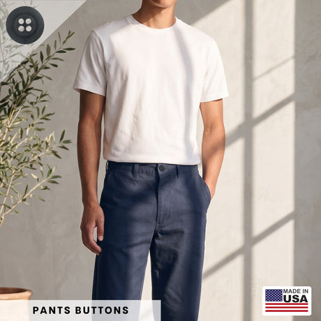 A man stands indoors near a plant, wearing a white t-shirt and navy pants fastened with Khakis, Chinos and Casual Cotton Pant Buttons; the Made in USA label is visible.