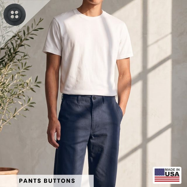 A man stands indoors near a plant, wearing a white t-shirt and navy pants fastened with Khakis, Chinos and Casual Cotton Pant Buttons; the Made in USA label is visible.