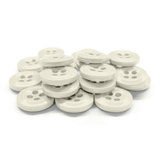 A stack of white Work Shirt Buttons with four holes arranged on a white background.