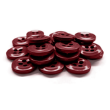 A stack of dark red Work Shirt Buttons with four holes arranged on a white surface.