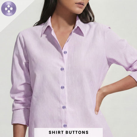 A woman stands with one hand on her hip, wearing a light purple button-up shirt with rolled sleeves that features Replacement Shirt Buttons.