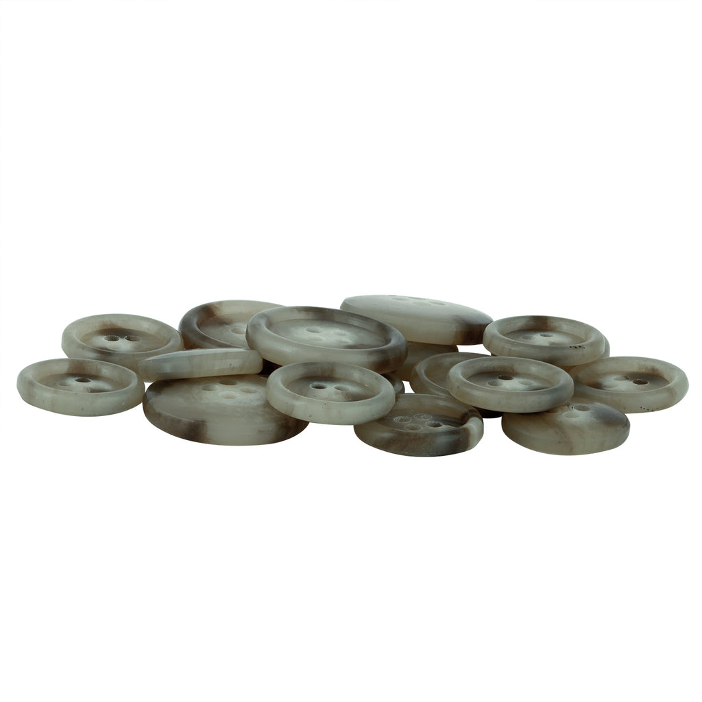 A pile of round, flat Vegan Faux Horn Suit Buttons in grayish-brown, each with four holes, is arranged on a white background.