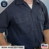 A man wearing a navy work shirt with buttoned chest pockets, featuring durable military spec buttons like those in the Work Shirt Buttons 22 Pack. Made in USA label in the corner.